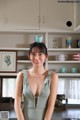 A woman standing in a kitchen holding a cup on her head.