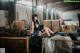 A woman sitting on top of a barrel in a warehouse.