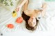 A woman laying on a bed with a fan and watermelon.