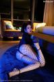 A woman in fishnet stockings sitting on a blue rug.