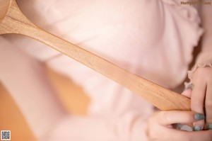 A woman holding a wooden spoon with a name engraved on it.