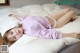 A woman laying on top of a bed in a pink sweater.