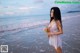 A woman standing on the beach holding a bouquet of flowers.