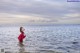 A woman in a red dress standing in the ocean.