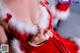 a woman in a santa claus outfit sitting next to a christmas tree