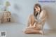 A woman sitting on the floor in a white lingerie.