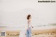 A woman walking on a beach near the ocean.