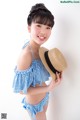 A young girl wearing a blue and white gingham bikini and a straw hat.