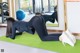 A woman doing a plank on a green mat in a gym.