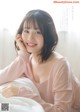 A woman in a pink shirt laying on a bed.