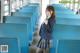 A woman in a school uniform standing on a train.